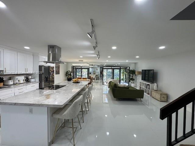 9709 North New River Canal Road, Unit 207 Plantation, FL 33324 - Photo 12 of 18 a kitchen with stainless steel appliances kitchen island granite countertop a refrigerator a stove a sink a dining table and chairs
