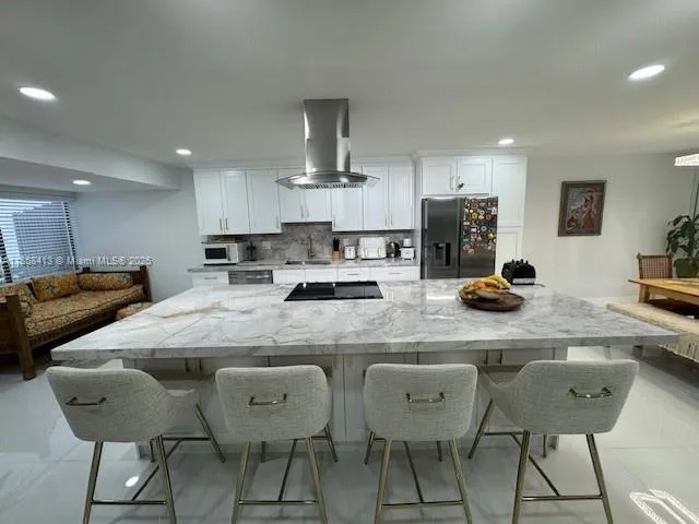 a kitchen with stainless steel appliances granite countertop a table chairs and a refrigerator