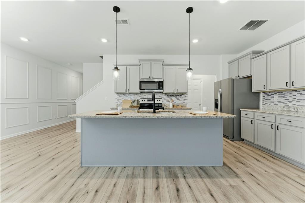 7492 Knoll Hollow Road Lithonia, GA 30058 - Photo 4 of 30 a kitchen with kitchen island white cabinets and stainless steel appliances