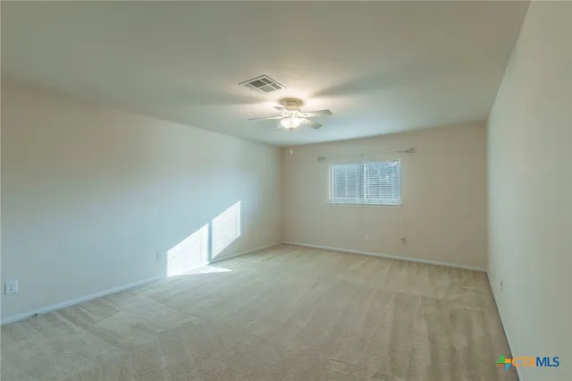 an empty room with a chandelier fan and windows