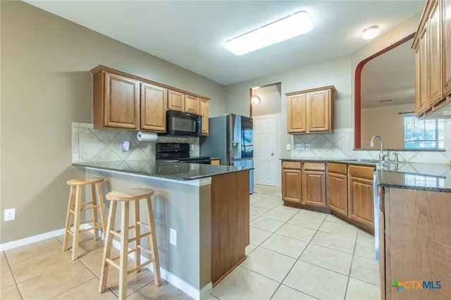 a kitchen with stainless steel appliances granite countertop a stove a sink a microwave a refrigerator and cabinets