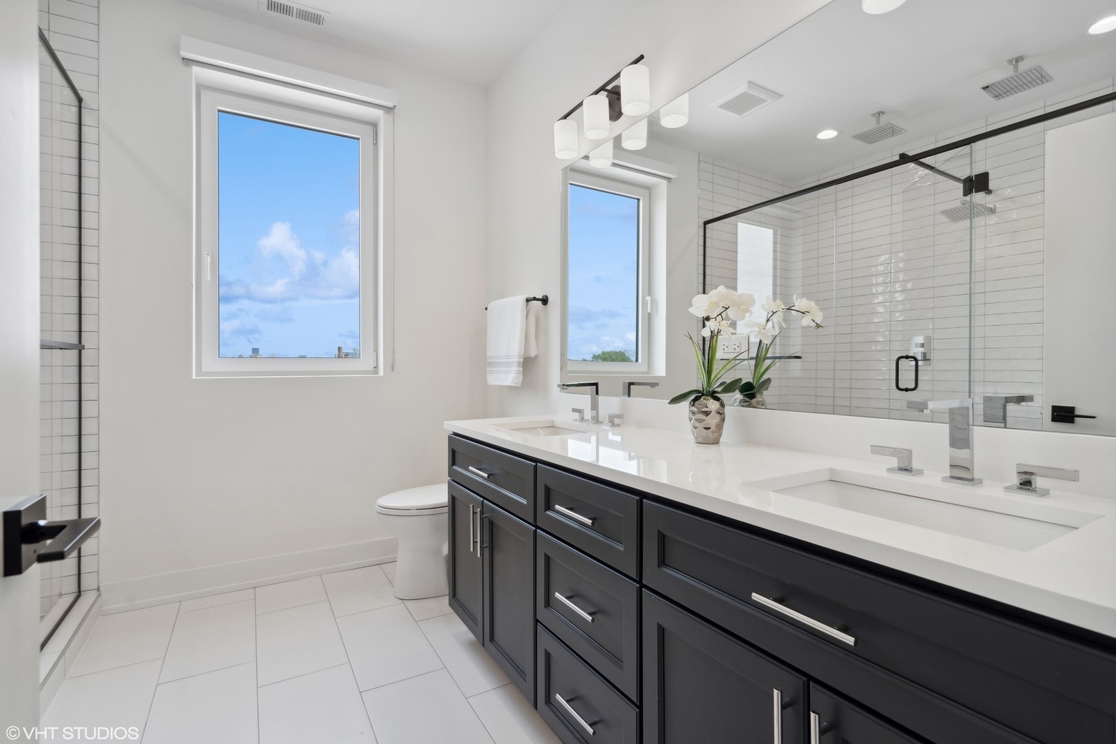 3335-3341 North Sheffield Avenue Chicago, IL 60657 - Photo 40 of 76 a bathroom with a double vanity sink a toilet and a mirror