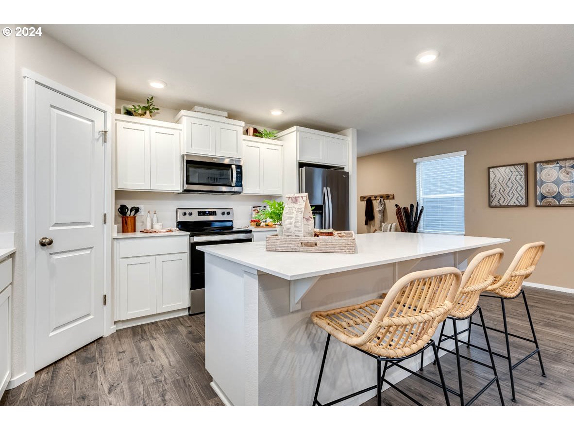 17406 Northwest 9th Avenue Ridgefield, WA 98642 - Photo 9 of 25 a kitchen with stainless steel appliances a stove a sink a microwave a refrigerator and white cabinets with wooden floor