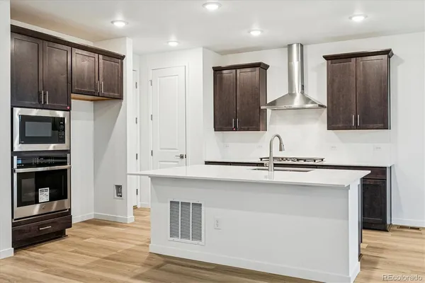 a kitchen with stainless steel appliances granite countertop a refrigerator a stove and a sink