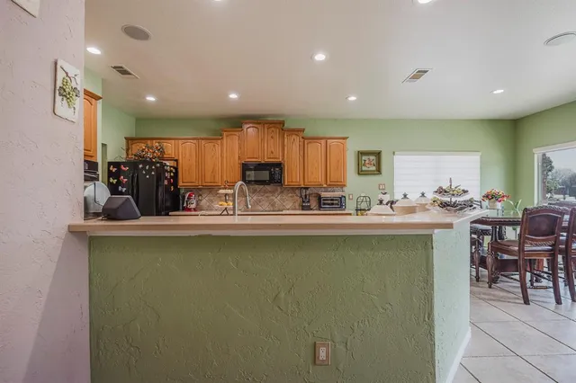 a kitchen with stainless steel appliances granite countertop a refrigerator a sink dishwasher a dining table and chairs with wooden floor