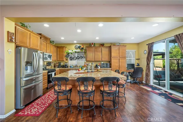 a kitchen with stainless steel appliances a dining table chairs and wooden floor