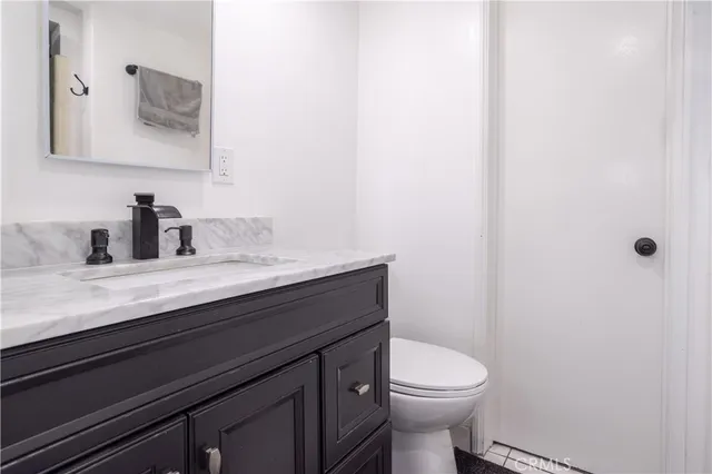 a bathroom with a granite countertop toilet sink and mirror