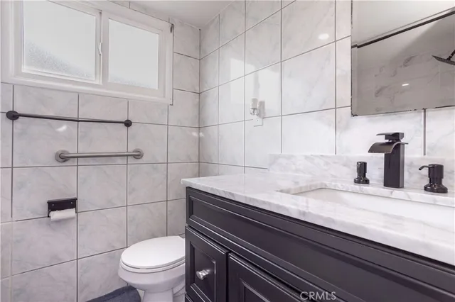 a bathroom with a granite countertop sink a toilet and shower