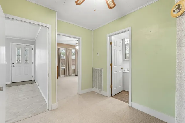 a view of an empty room and chandelier fan