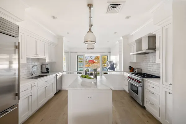 a large kitchen with stainless steel appliances granite countertop a stove oven and a white cabinets