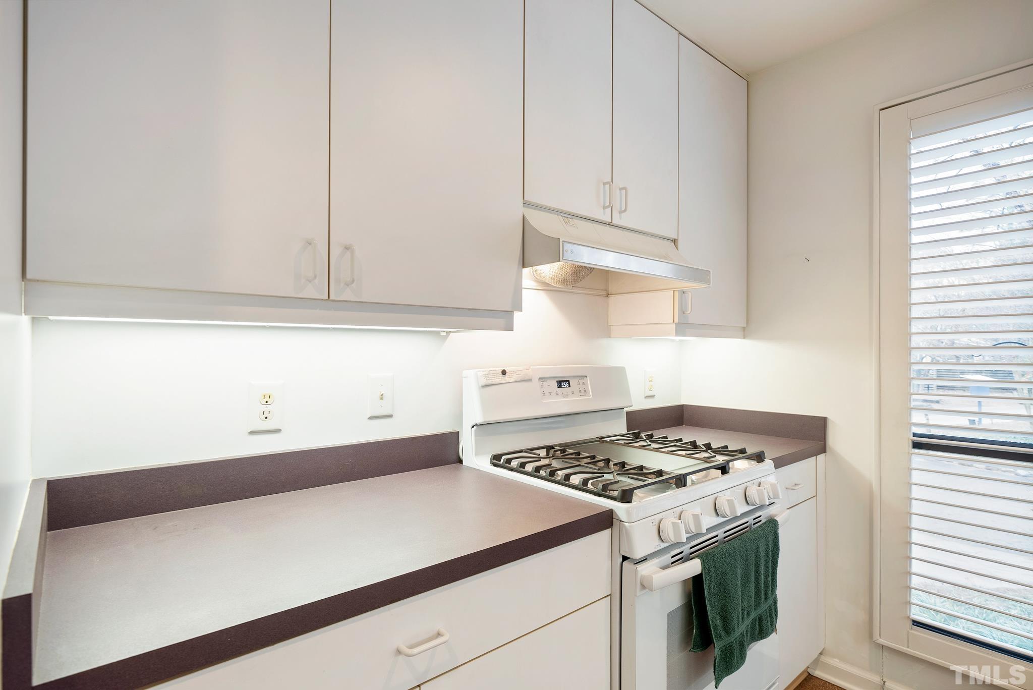 2742 Rue Sans Famille Raleigh, NC 27607 - Photo 7 of 21 a kitchen with granite countertop a stove a sink and a white cabinets