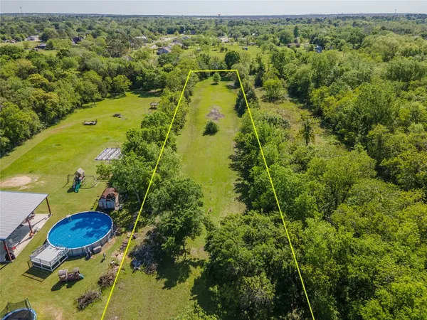 an aerial view of residential houses with outdoor space and trees