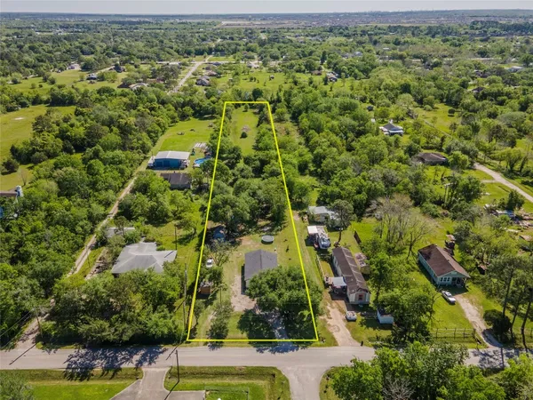 an aerial view of residential houses with outdoor space and trees