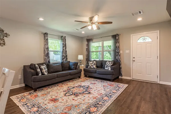 a living room with stainless steel appliances kitchen island granite countertop furniture wooden floor and a rug