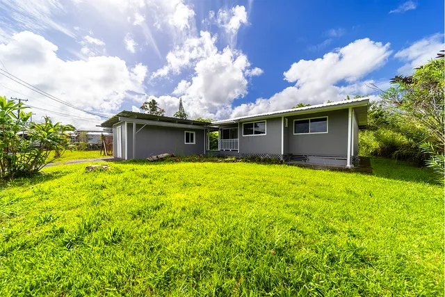 a front view of house with yard and trees in the background