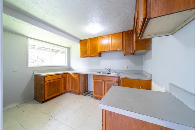 a kitchen with stainless steel appliances granite countertop a sink a stove top oven a chimney and a window