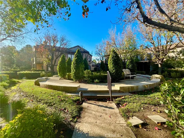 a view of a house with a yard plants and large tree