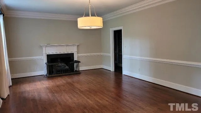 a view of an empty room with wooden floor and a fireplace