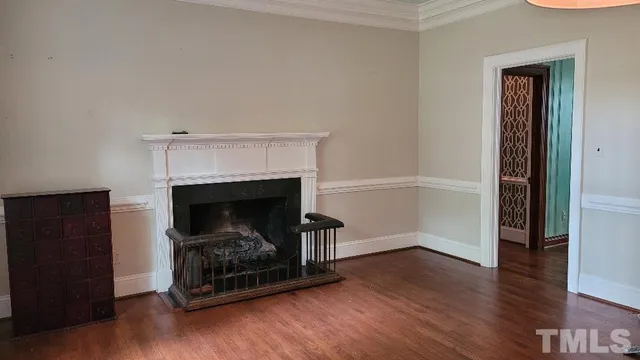 an empty room with wooden floor a fireplace and window