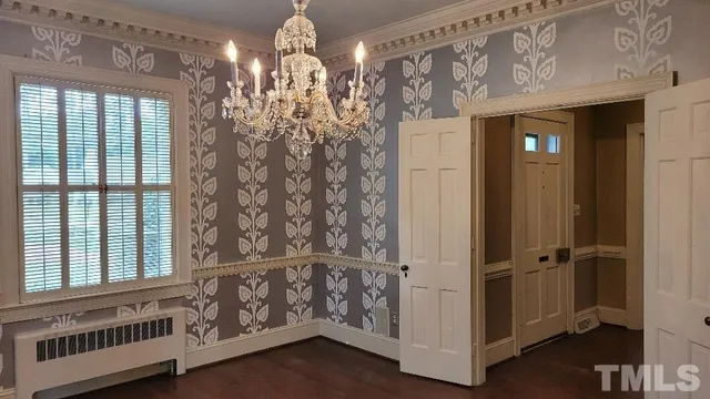 a view of a livingroom with chandelier front door and wooden floor