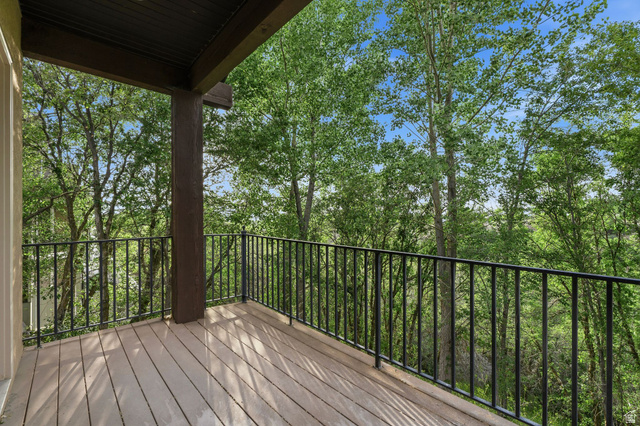 1429 Chateau Ridge Way Sandy, UT 84092 - Photo 7 of 22 Covered balcony featuring wood-finish decking and black metal railings surrounded by mature trees