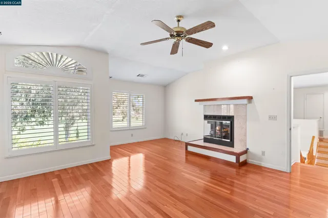 a view of empty room with wooden floor and fan