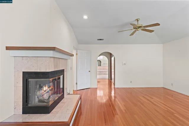 a view of an empty room with wooden floor fireplace and a window