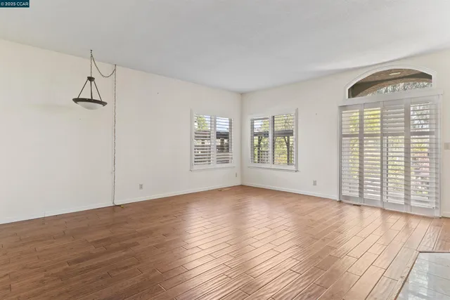 wooden floor fireplace and windows in an empty room