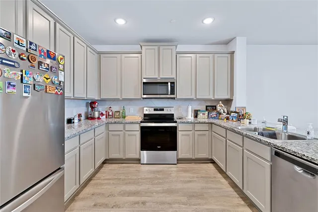 a kitchen with stainless steel appliances granite countertop a refrigerator sink and stove top oven