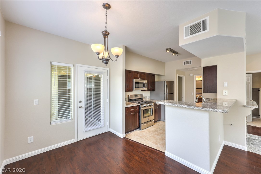 9050 West Warm Springs Road, Unit 2033 Las Vegas, NV 89148 - Photo 12 of 30 A kitchen and dining area featuring rich hardwood floors and modern stainless steel appliances.