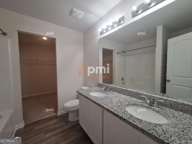a bathroom with a granite countertop sink a toilet a large mirror and shower