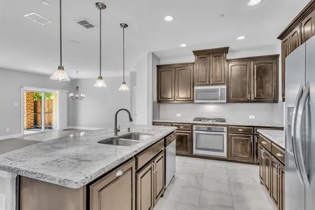 a kitchen with stainless steel appliances granite countertop a sink a stove and a refrigerator