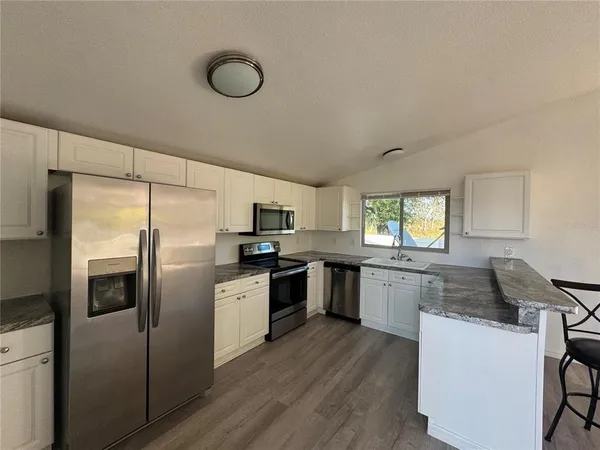 a kitchen with granite countertop a sink cabinets stainless steel appliances and a window
