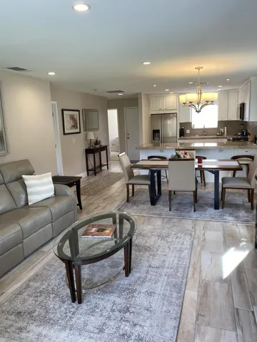 a living room with furniture a rug and kitchen view