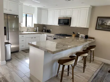 a kitchen with stainless steel appliances granite countertop a stove a sink a microwave a refrigerator and white cabinets