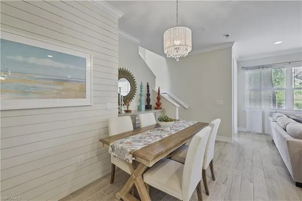 a dining room with wooden floor a chandelier a wooden table and chairs