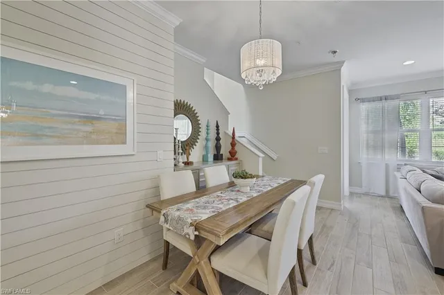 a dining room with wooden floor a chandelier a wooden table and chairs