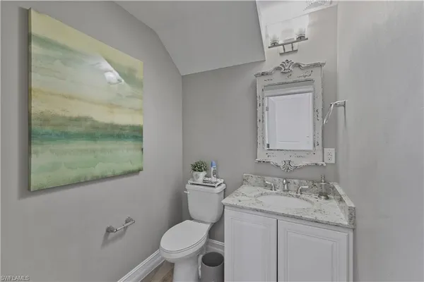 a bathroom with a granite countertop toilet a sink and mirror