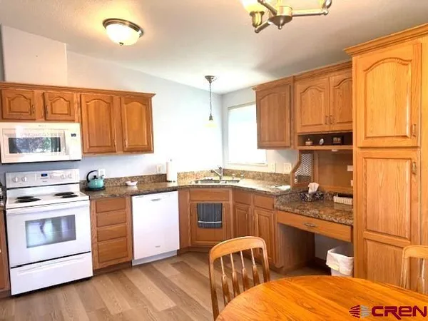 a kitchen with stainless steel appliances granite countertop a stove top oven a sink dishwasher and white cabinets with wooden floor