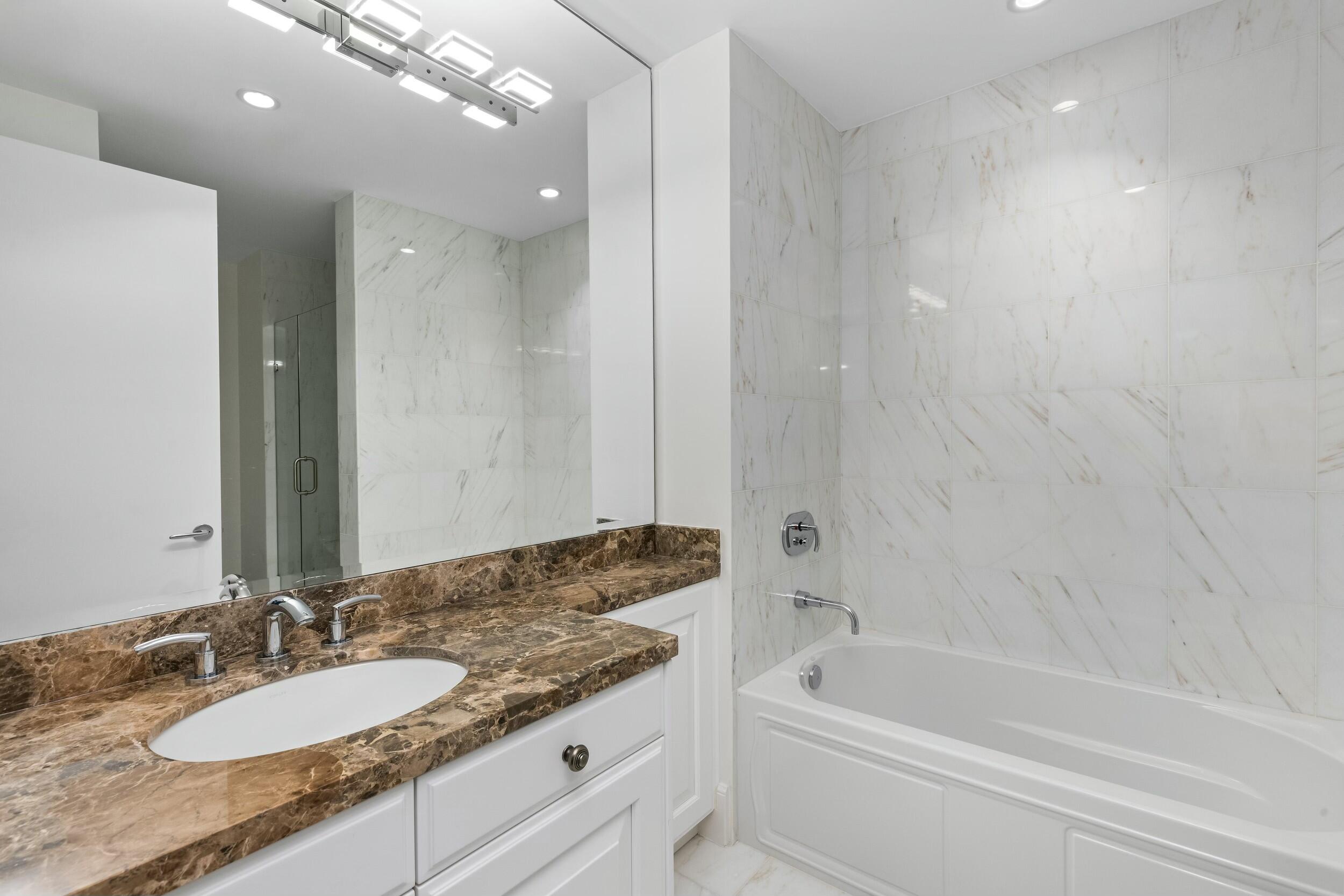2500 South Ocean Boulevard, Unit 903 Boca Raton, FL 33432 - Photo 52 of 66 a bathroom with a granite countertop bathtub a sink and a mirror