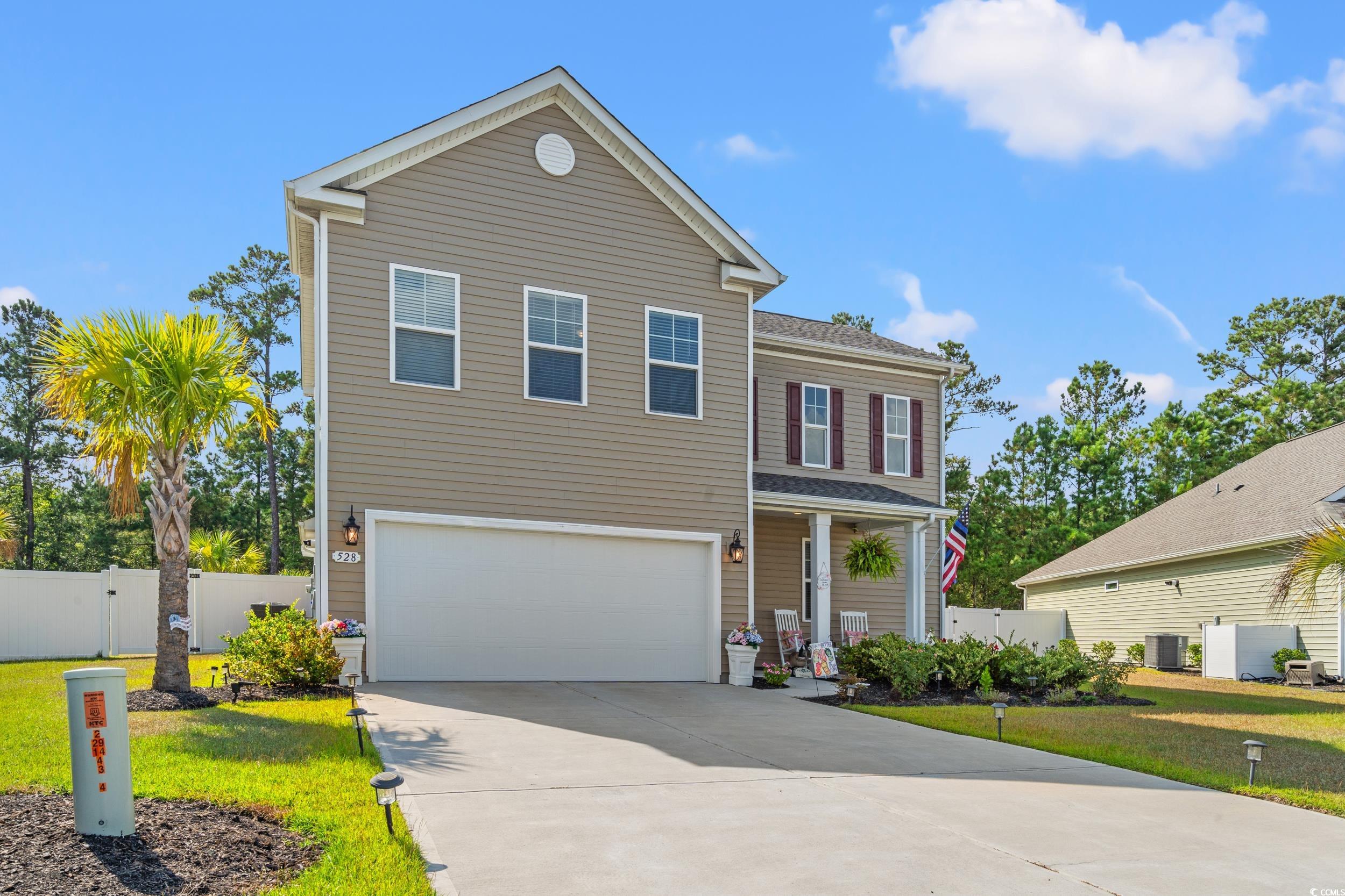 Traditional-style home with concrete driveway, a garage, and a porch
