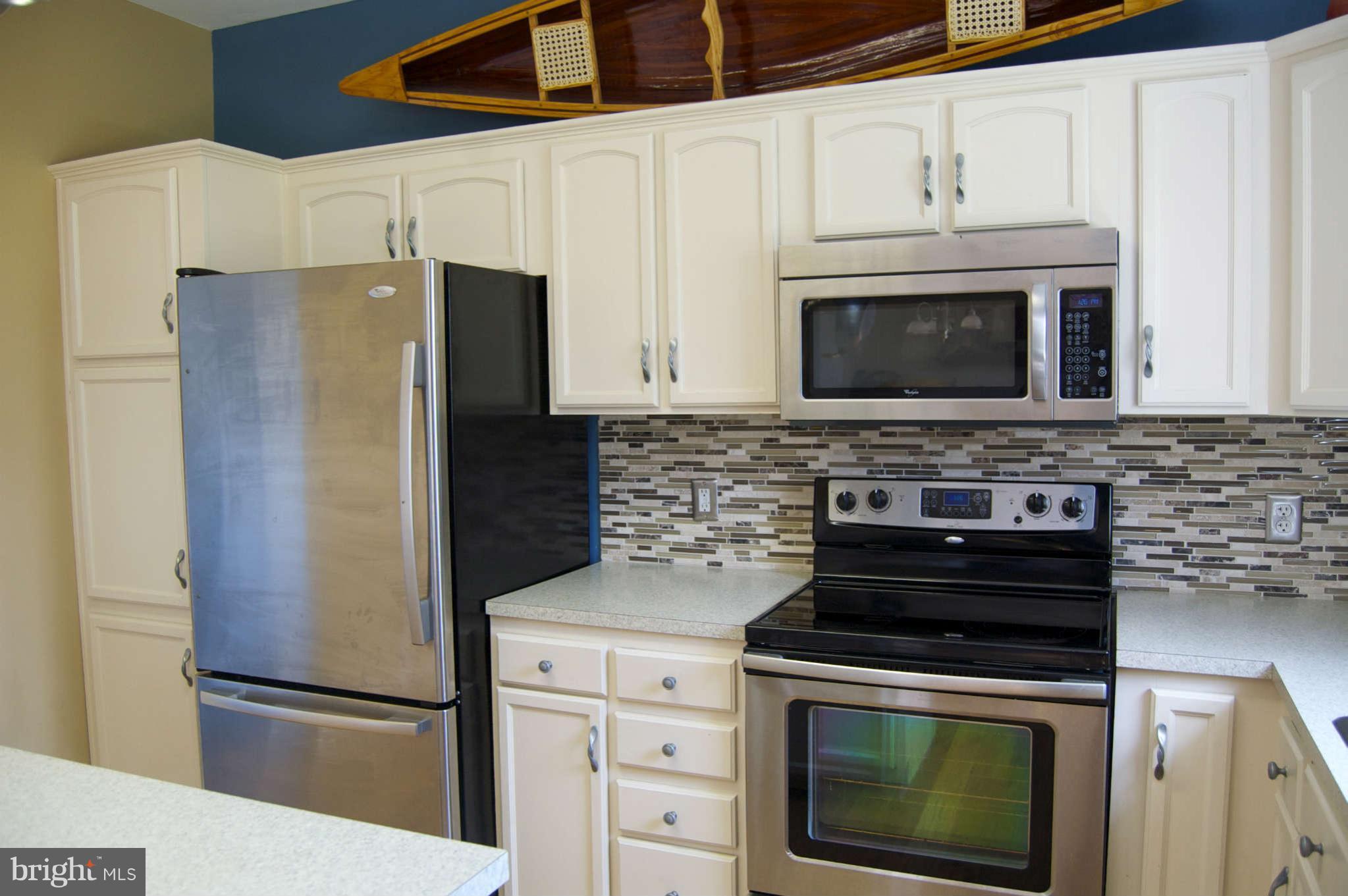 407 Stringtown Road Berryville, VA 22611 - Photo 9 of 30 a kitchen with stainless steel appliances white cabinets white stove a refrigerator and a microwave