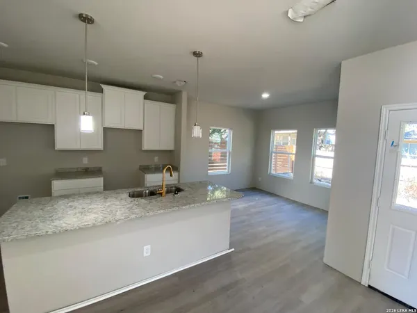 a kitchen with granite countertop a sink a counter space appliances and cabinets