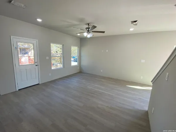 an empty room with windows and ceiling fan