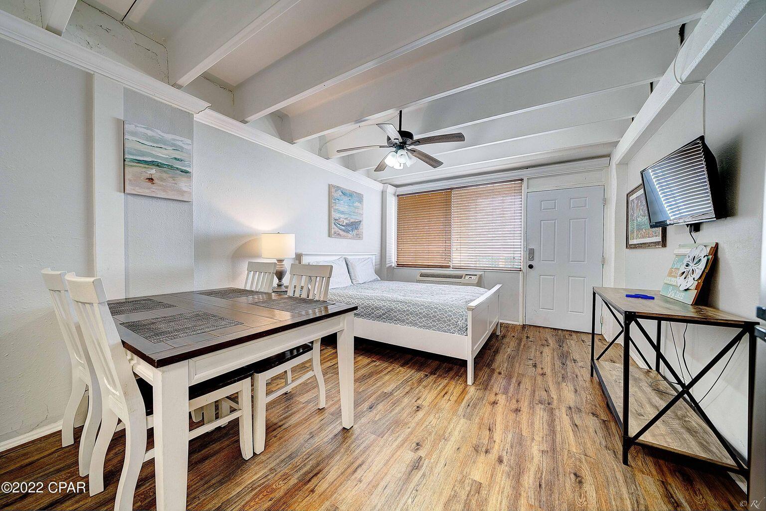 14401 Front Beach Road, Unit 434 Panama City Beach, FL 32413 - Photo 6 of 36 a room with a table chairs wooden floor and a ceiling fan