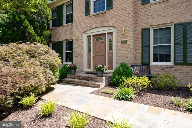 a view of a house with potted plants and a bench