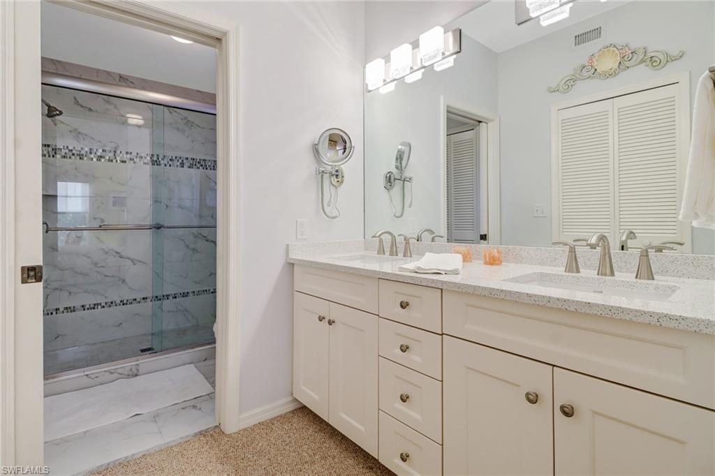 7108 Barrington Circle, Unit 101 Naples, FL 34108 - Photo 17 of 30 a bathroom with double vanity sink and shower