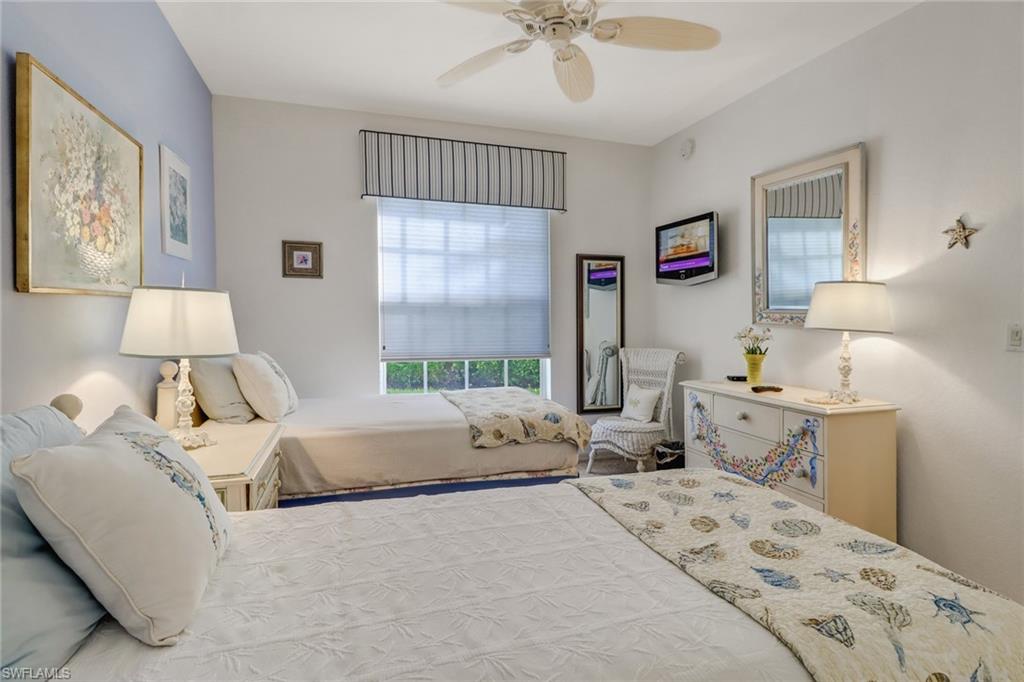 7108 Barrington Circle, Unit 101 Naples, FL 34108 - Photo 20 of 30 a bedroom with a large bed and a chandelier