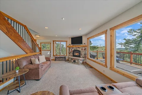 a living room with furniture a fireplace and a floor to ceiling window
