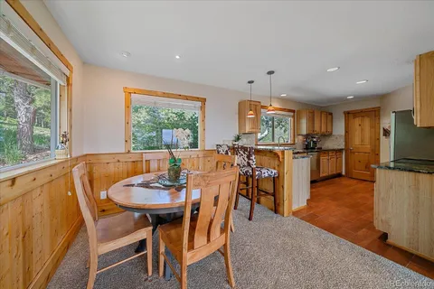 a kitchen with stainless steel appliances granite countertop a stove top oven a sink a dining table and chairs with wooden floor